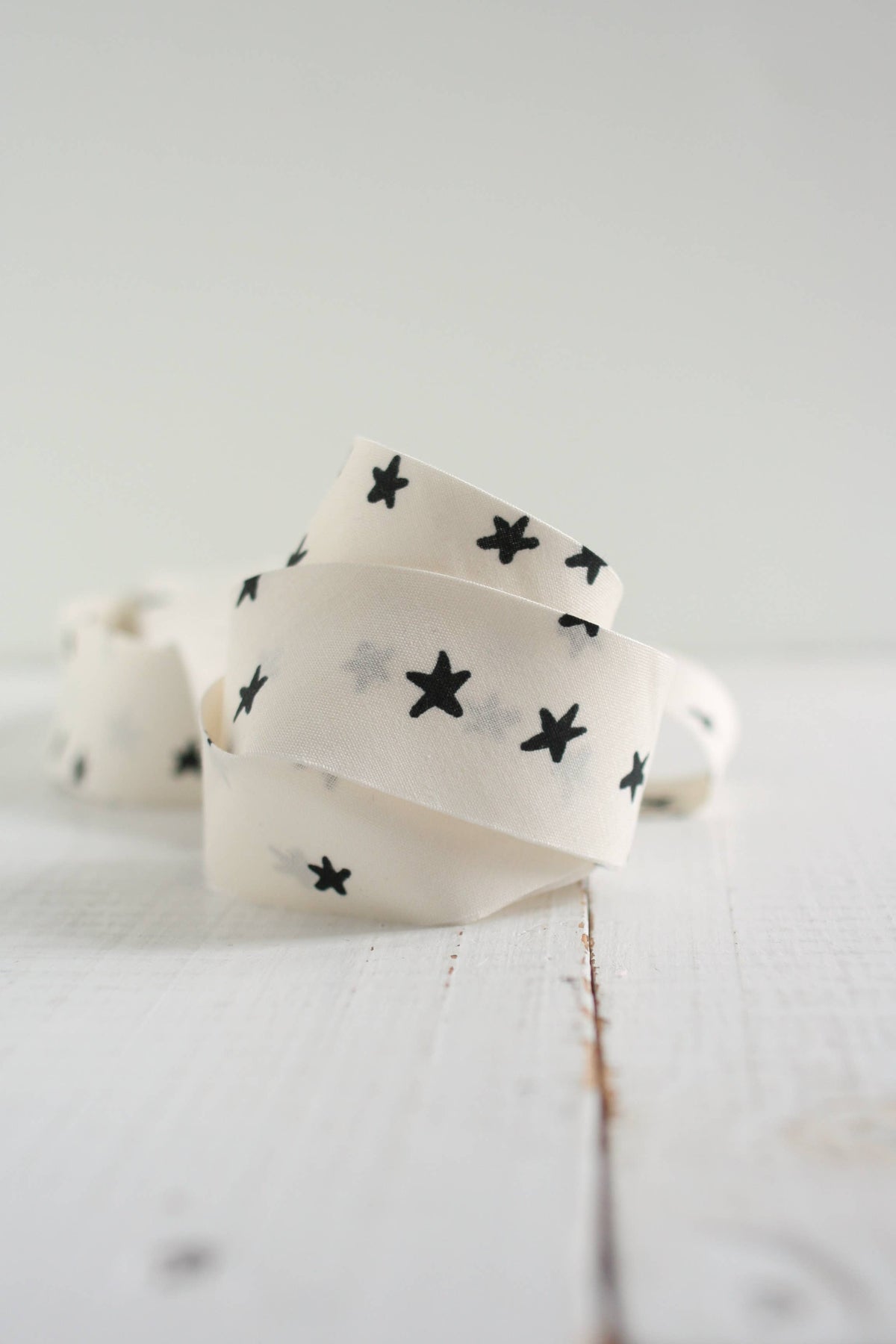 White ribbon with black star patterns on a light wooden surface