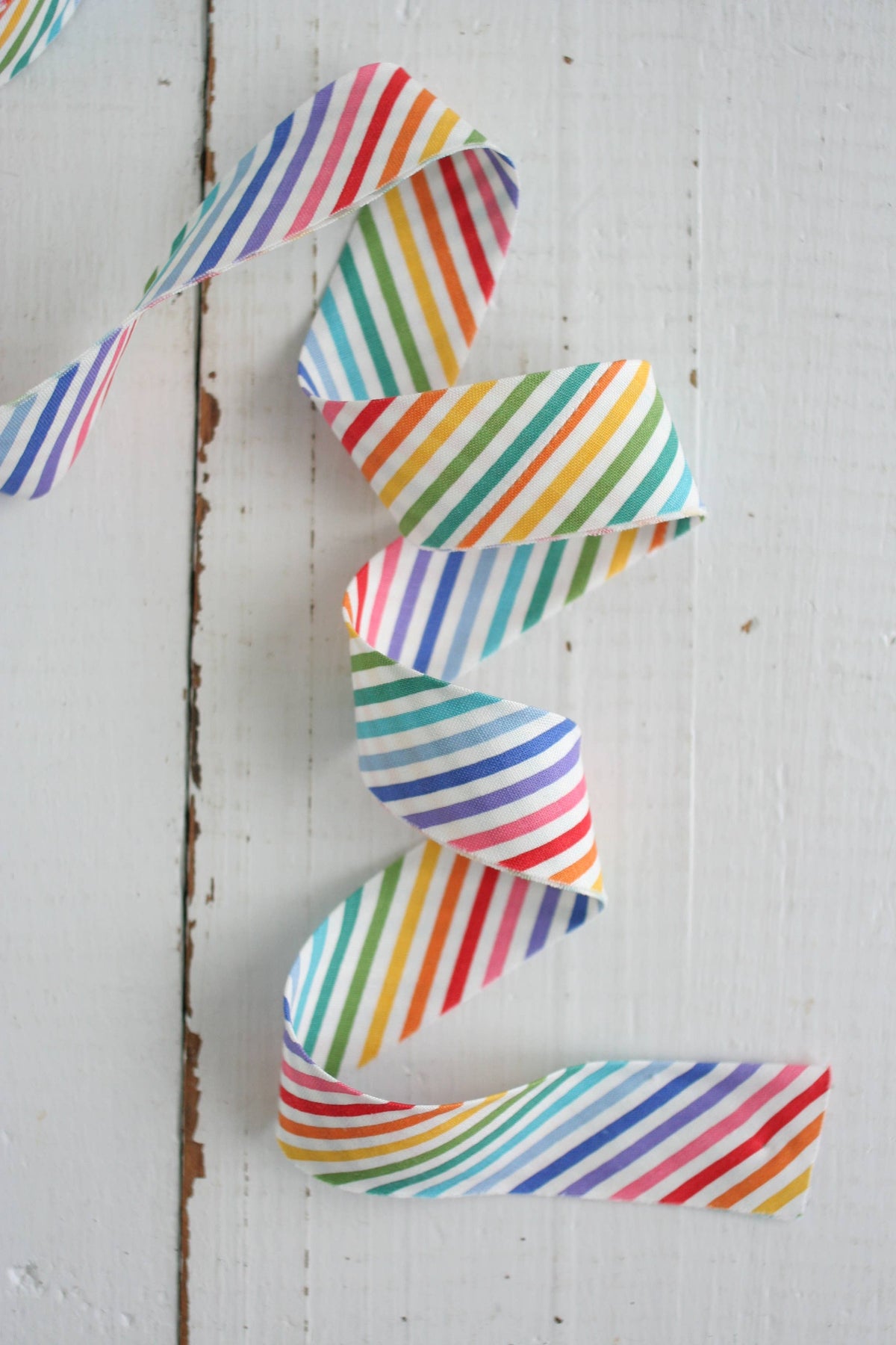 Colorful striped bias quilt binding on a white wooden background