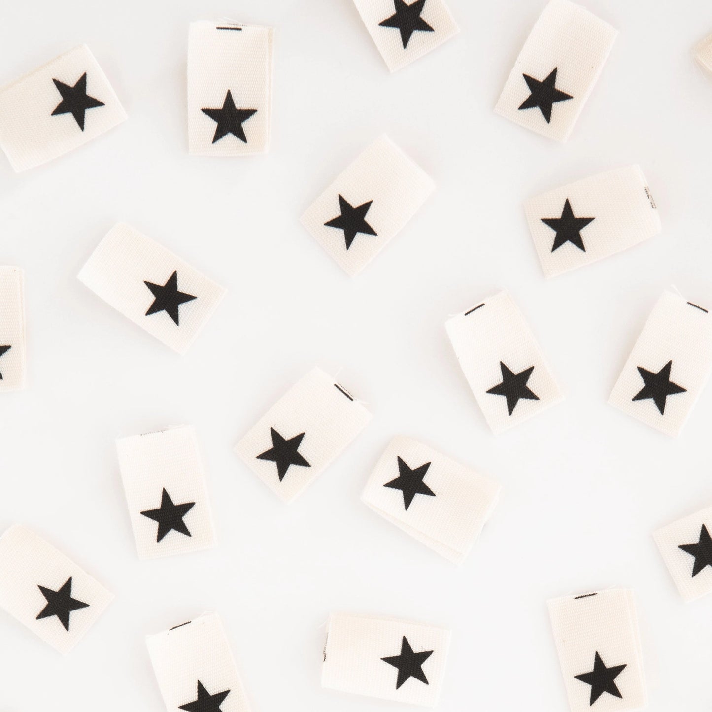 White tags with black stars arranged randomly on a light gray background