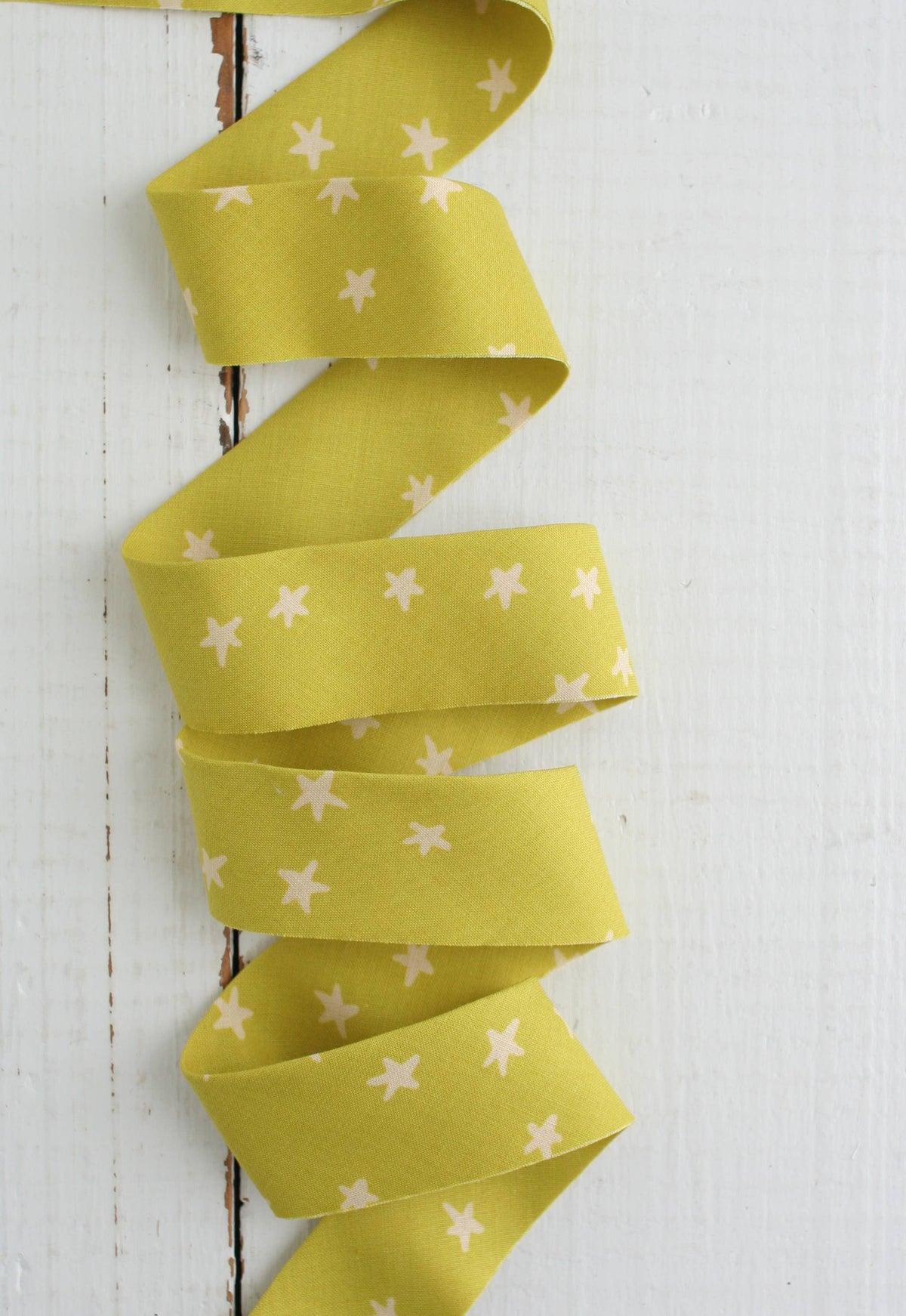 Yellow ribbon with white star pattern on a white wooden background