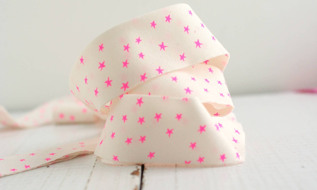 Pink star-patterned bias quilt binding on a white surface