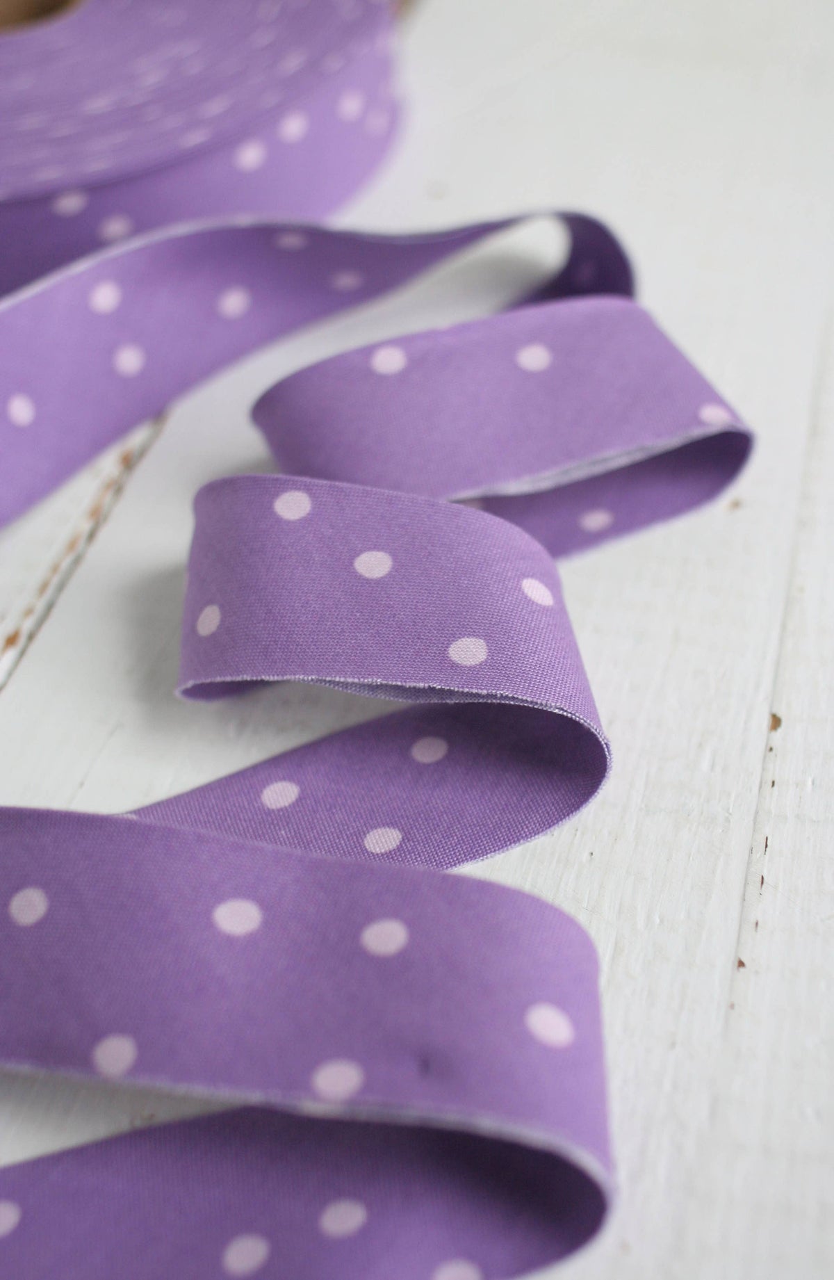 Purple ribbon with white polka dots on a light wooden surface