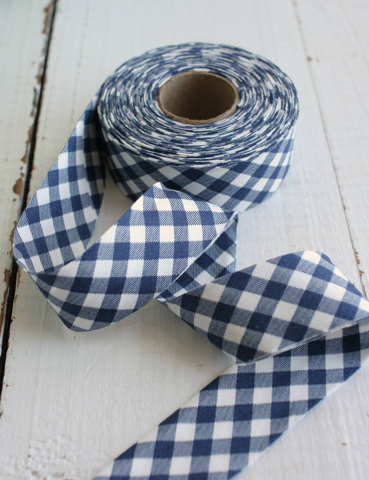 navy blue and white gingham bias quilt binding on a distressed white wooden surface.