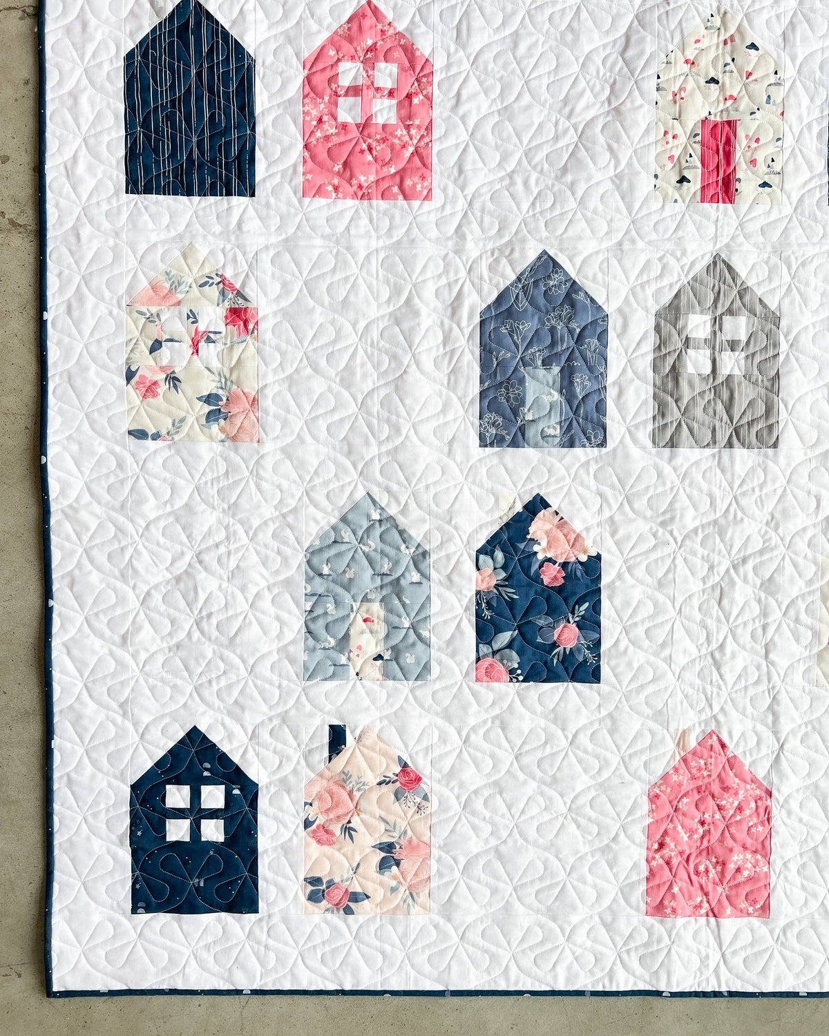 Quilt with house-shaped blocks in various colors and patterns on a white background