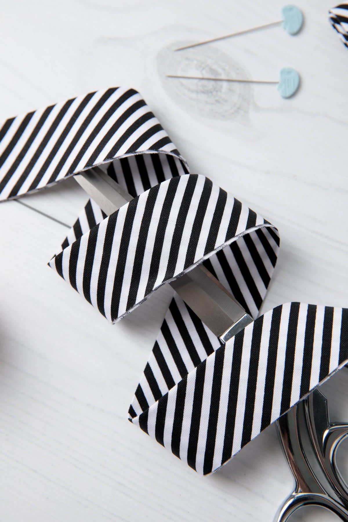 Black and white striped fabric pieces on a white background with scissors.