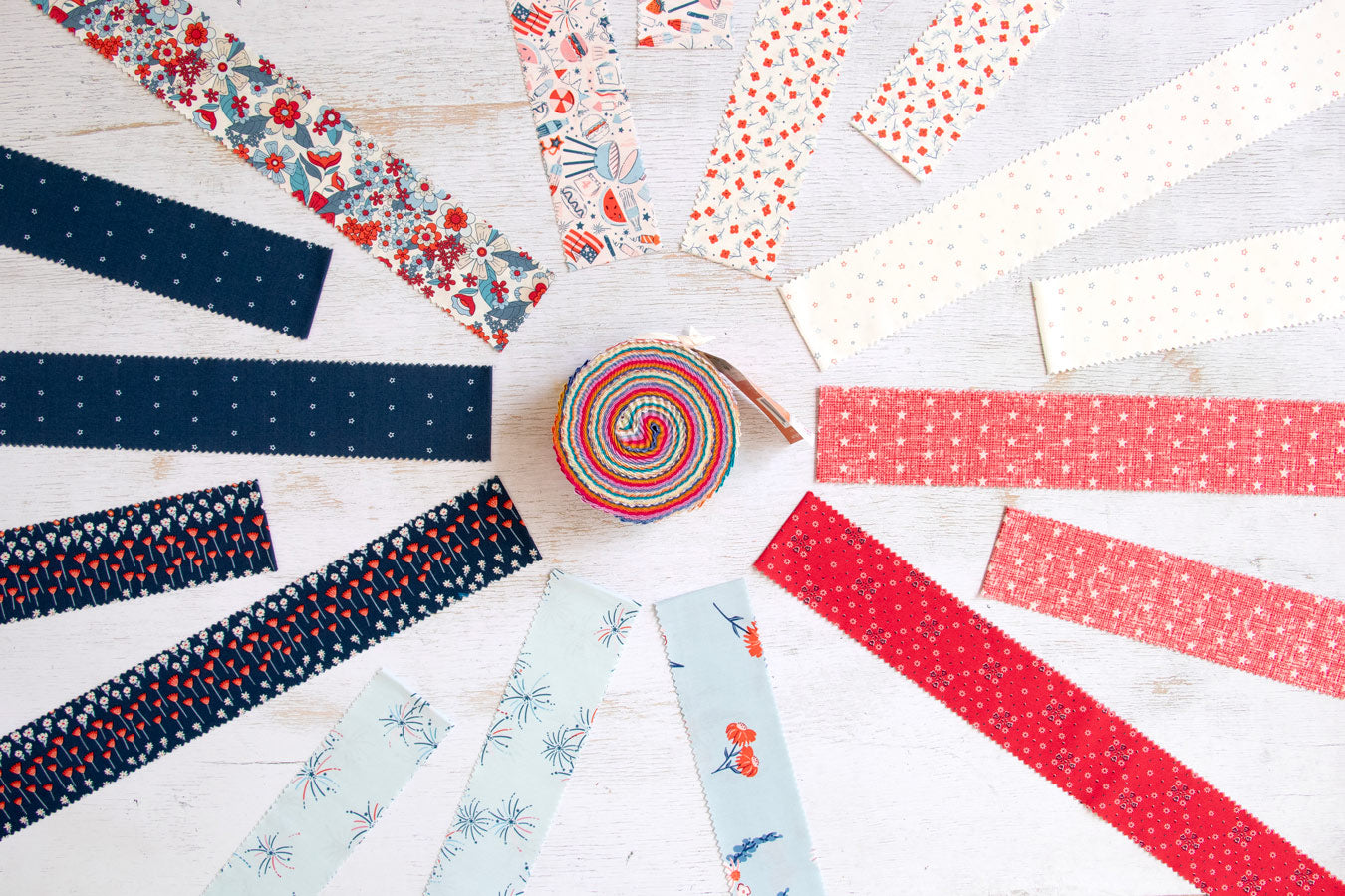 Collection of colorful fabric strips arranged in a circular pattern on a light wooden surface.