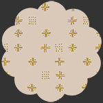 A scalloped beige fabric or paper swatch with a repeating pattern of small gold stars, crosses, and dotted motifs on a dark gray background.