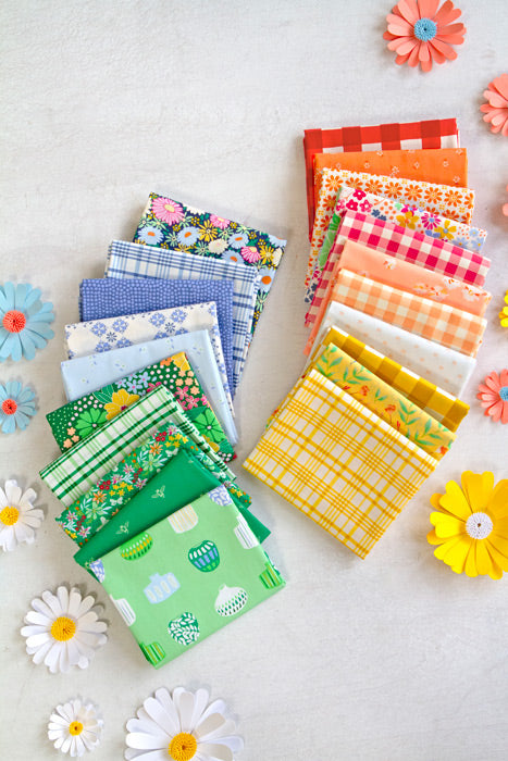Collection of colorful fabric swatches arranged on a light surface with decorative flowers.