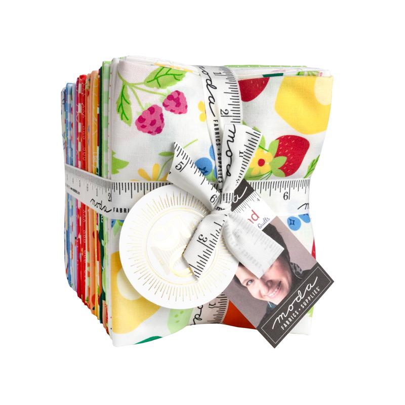 Collection of colorful fabric squares with a ruler and rotary cutter on a white background