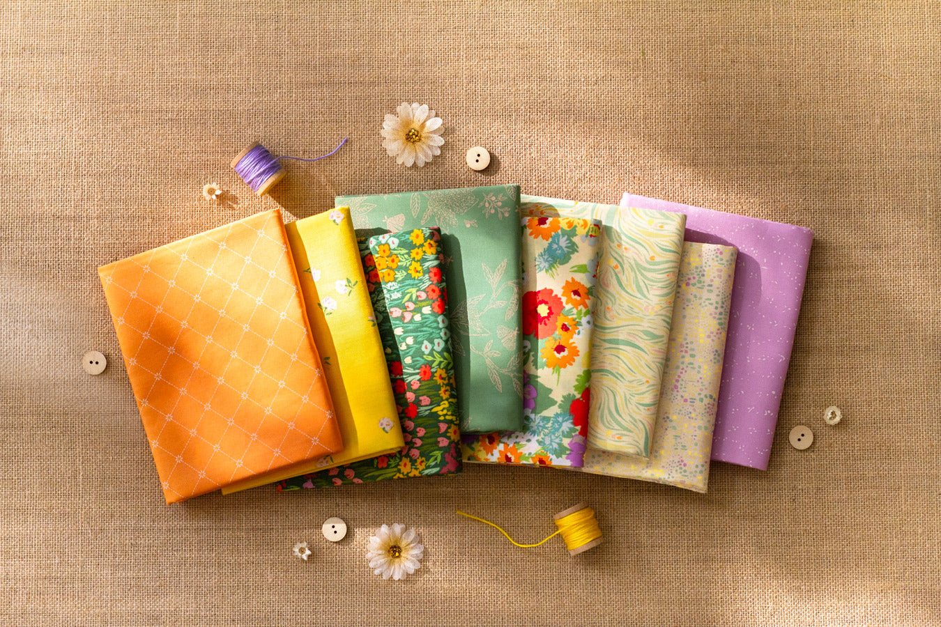 Set of colorful fabric swatches on a textured surface with buttons and yarn.