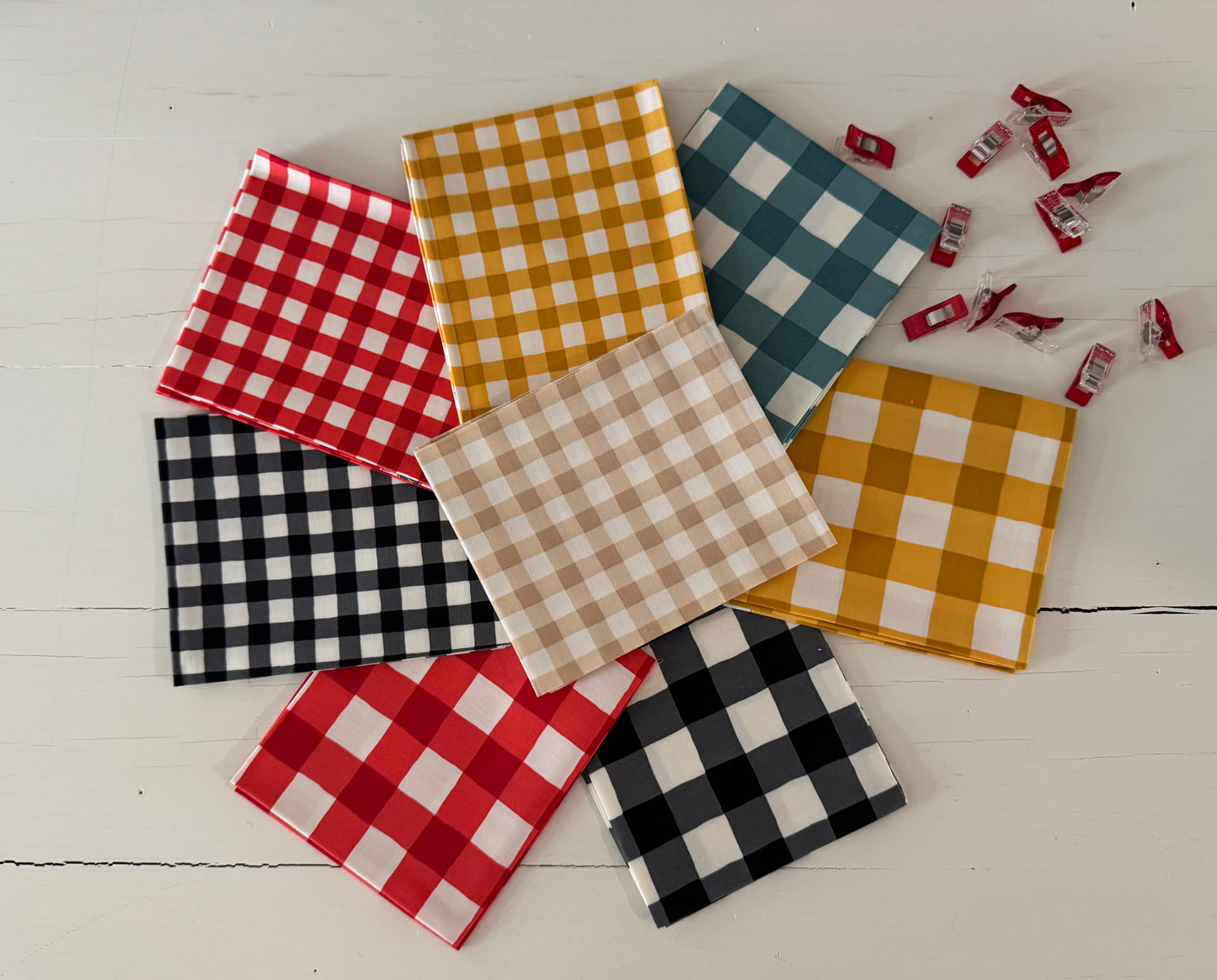 Collection of checkered fabric samples in various colors on a white surface.