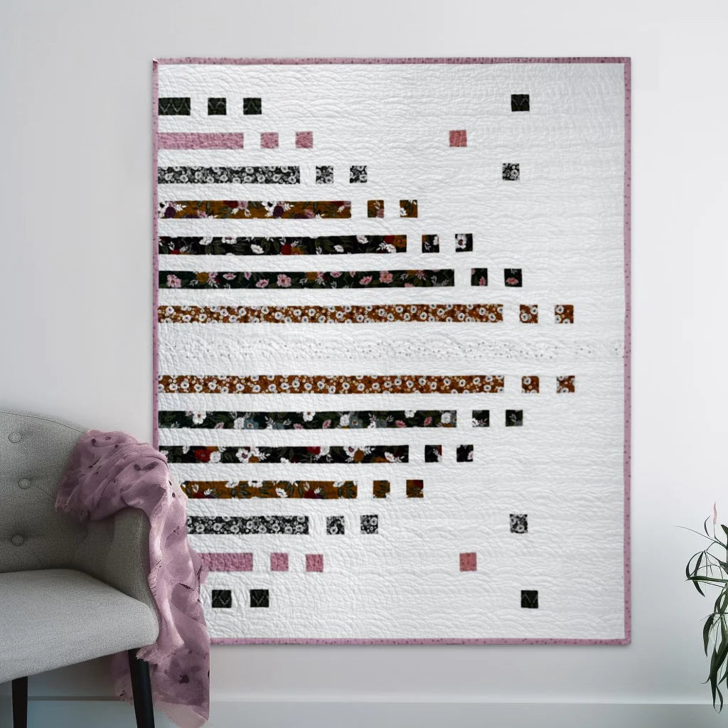 picture of a quilt on al wall. It is a strip quilt named Parallel Poet
