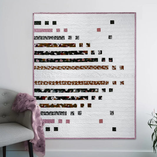 picture of a quilt on al wall. It is a strip quilt named Parallel Poet