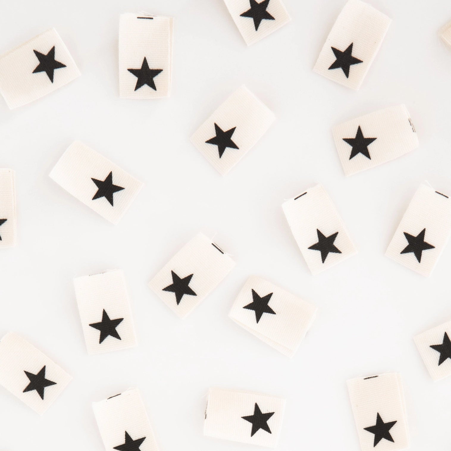 White tags with black stars arranged randomly on a light gray background