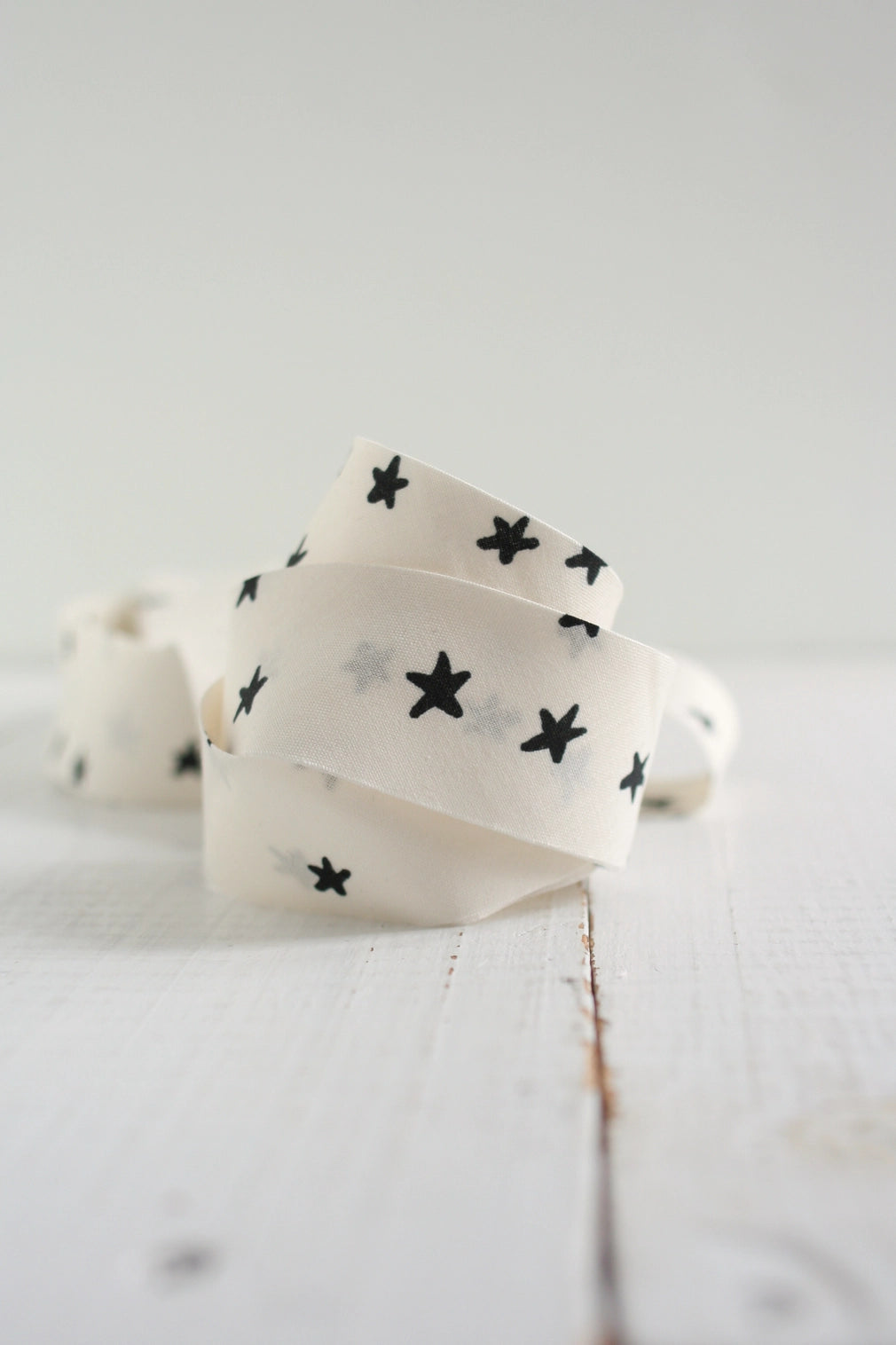 White bias tape with black star patterns on a light wooden surface