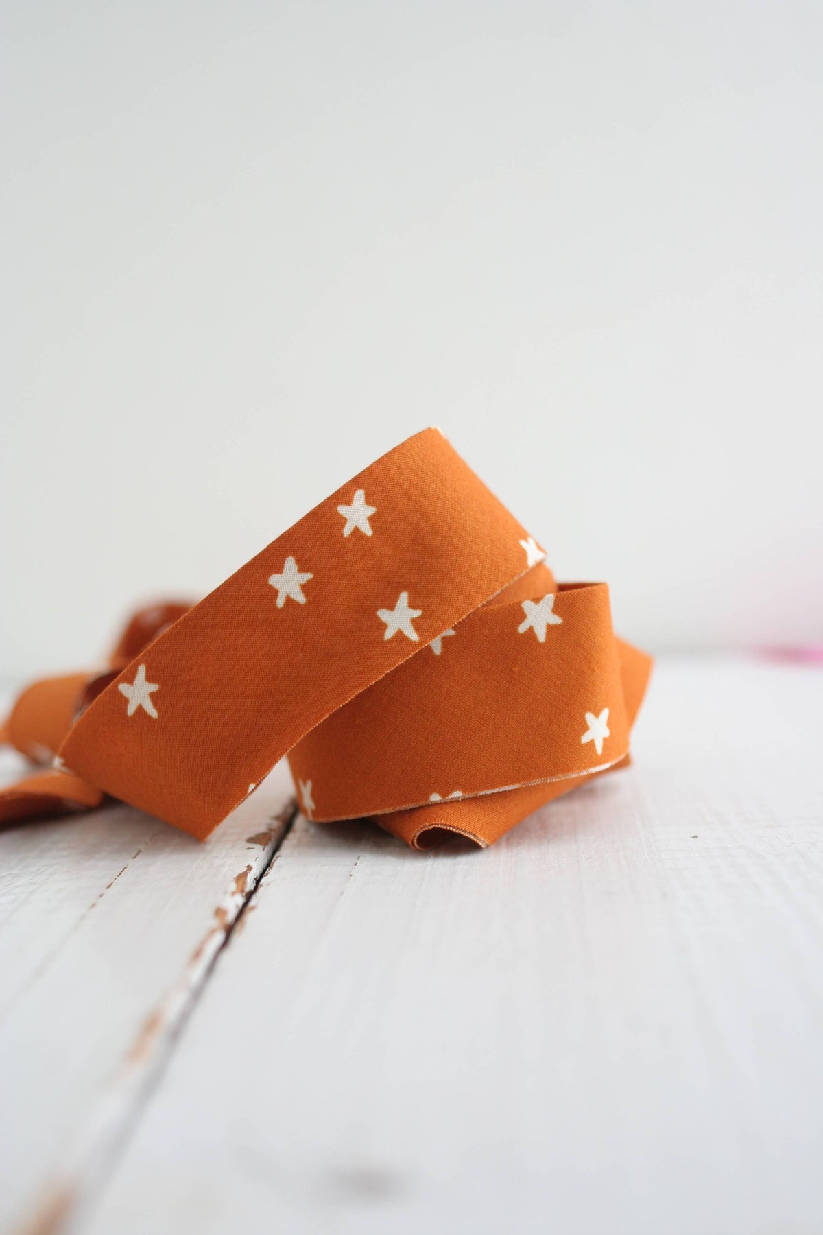 Orange ribbon with white star patterns on a light wooden surface