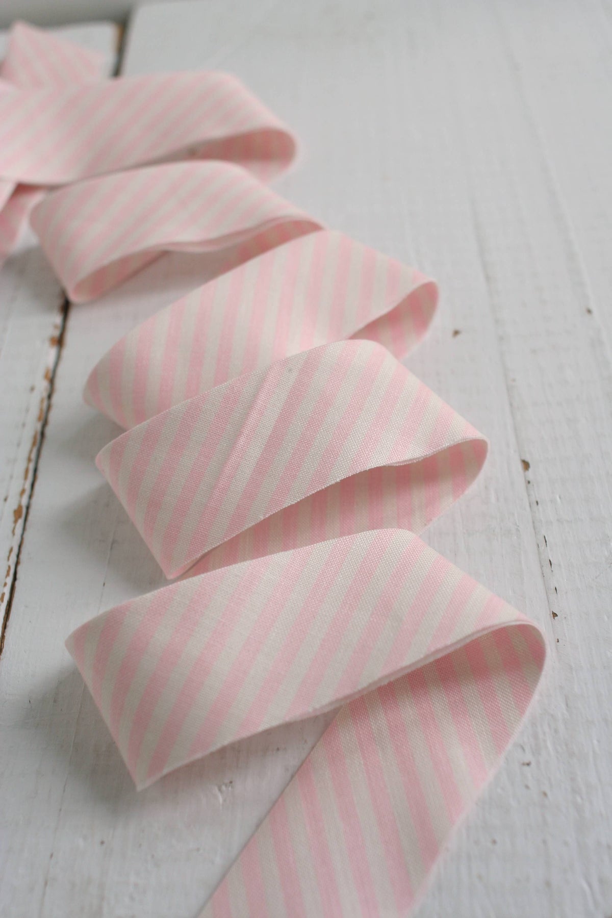 Pink striped ribbon on a white wooden surface