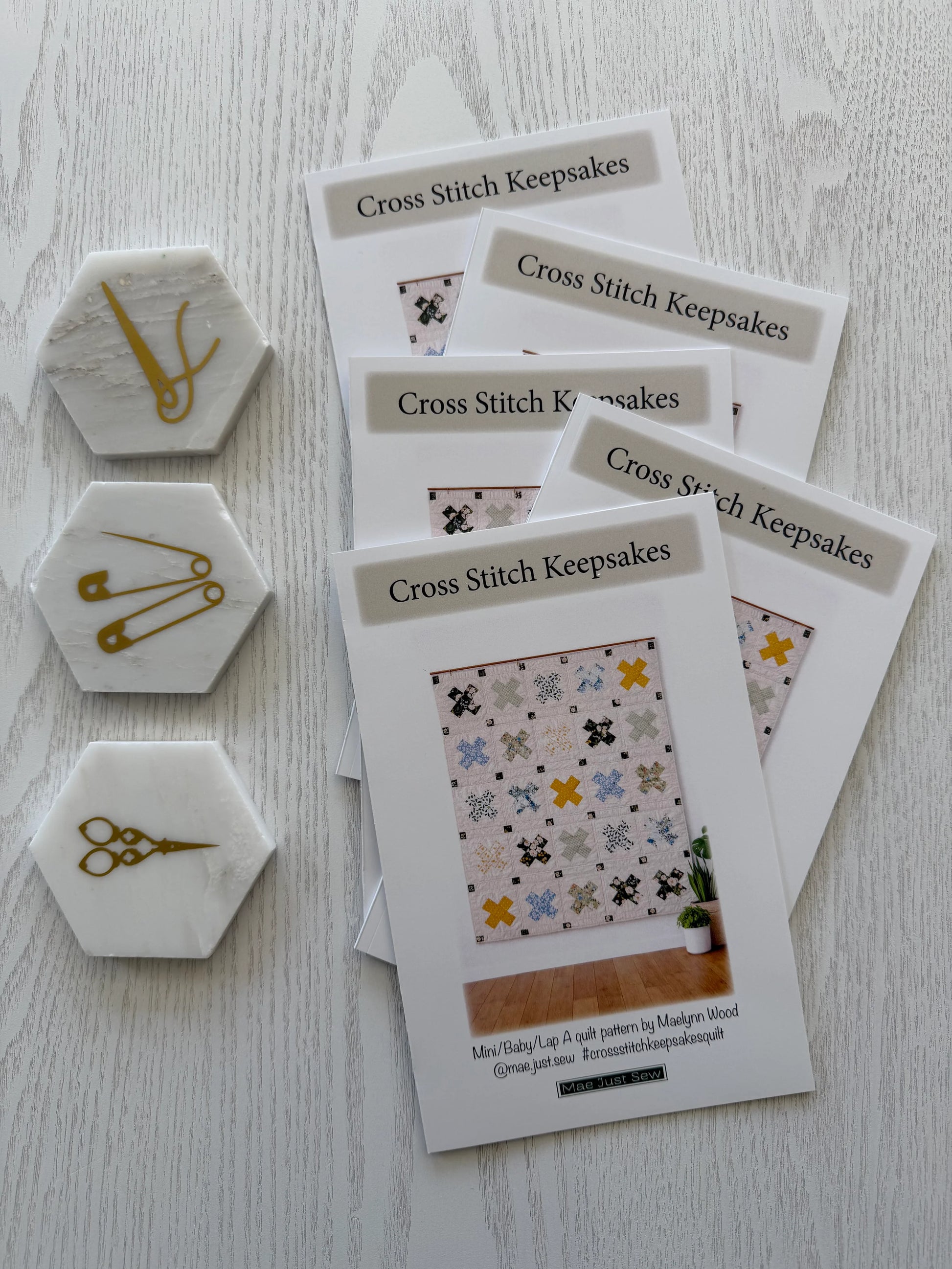 Cross Stitch Keepsakes pattern books with decorative pins on a light wooden surface