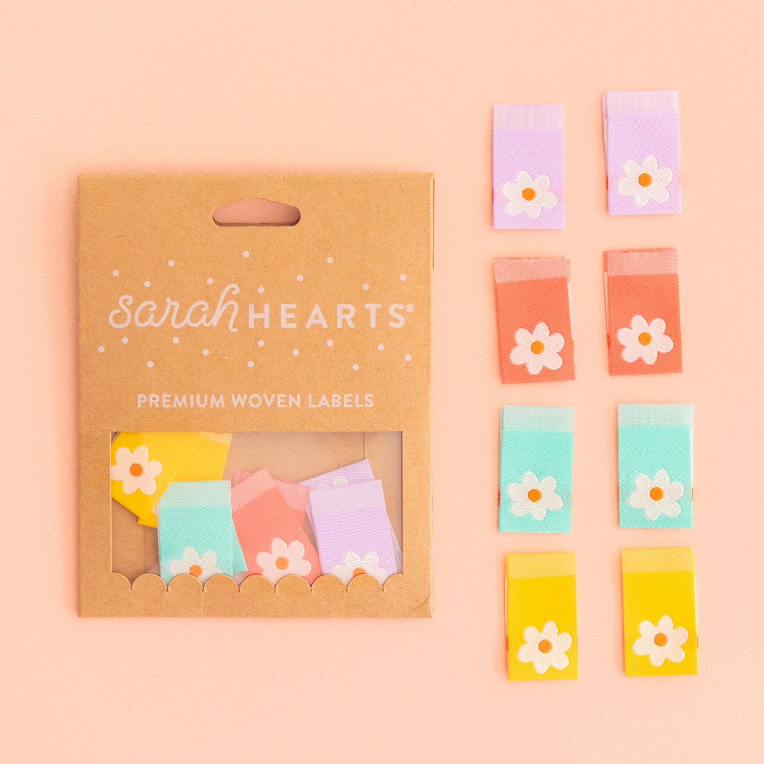Packaging of 'sarahHEARTS' premium woven labels with colorful labels on a pink background