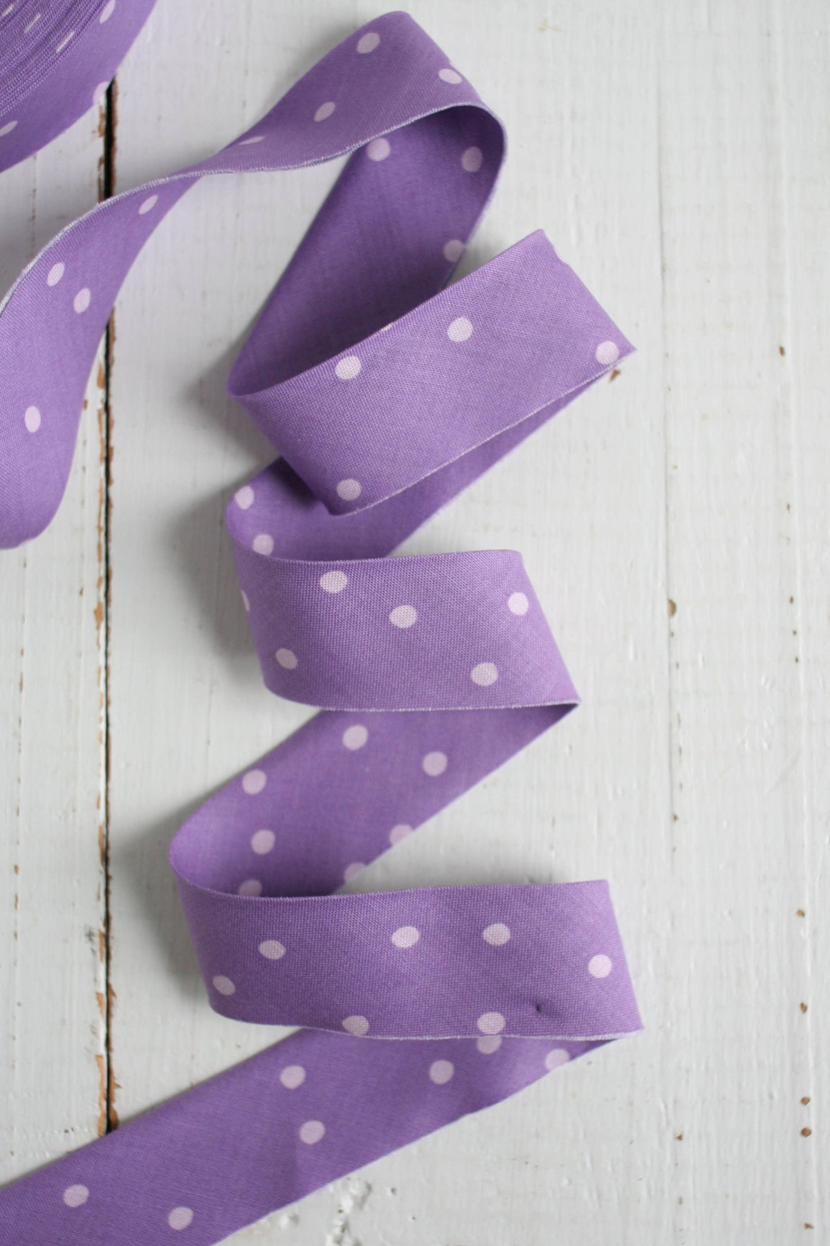 Purple ribbon with white polka dots on a light wooden surface