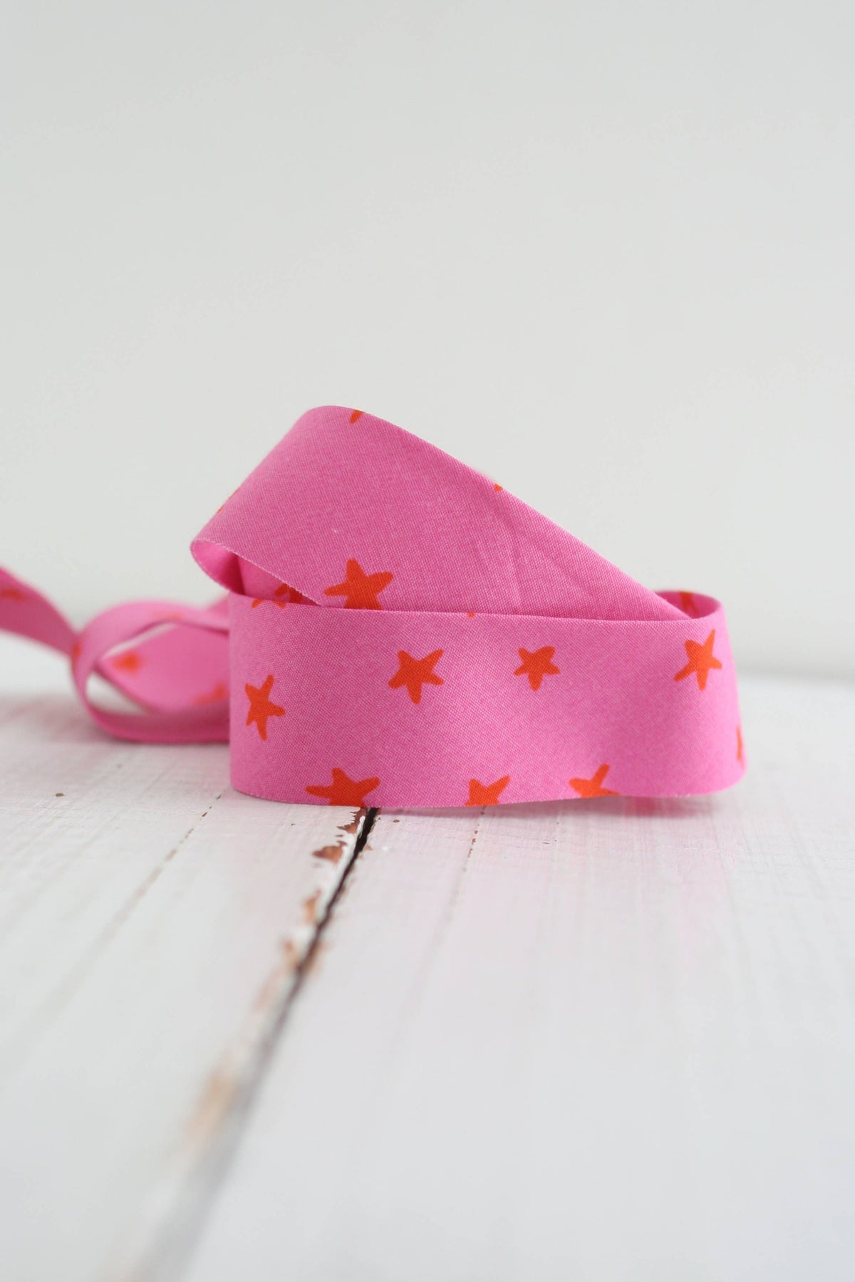 Pink headband with orange star patterns on a light wooden surface