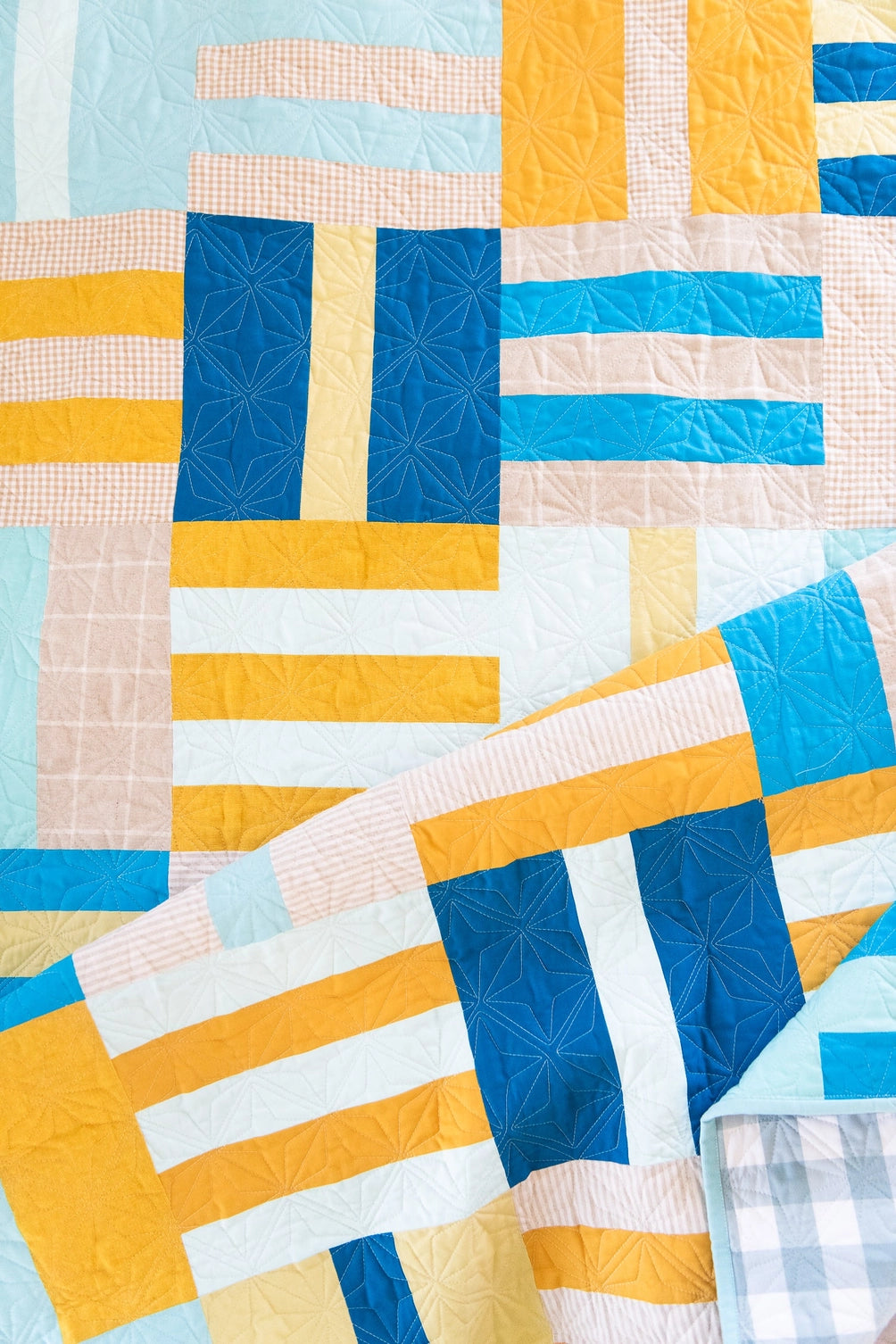 Colorful quilt with geometric pattern in blue, yellow, and white.
