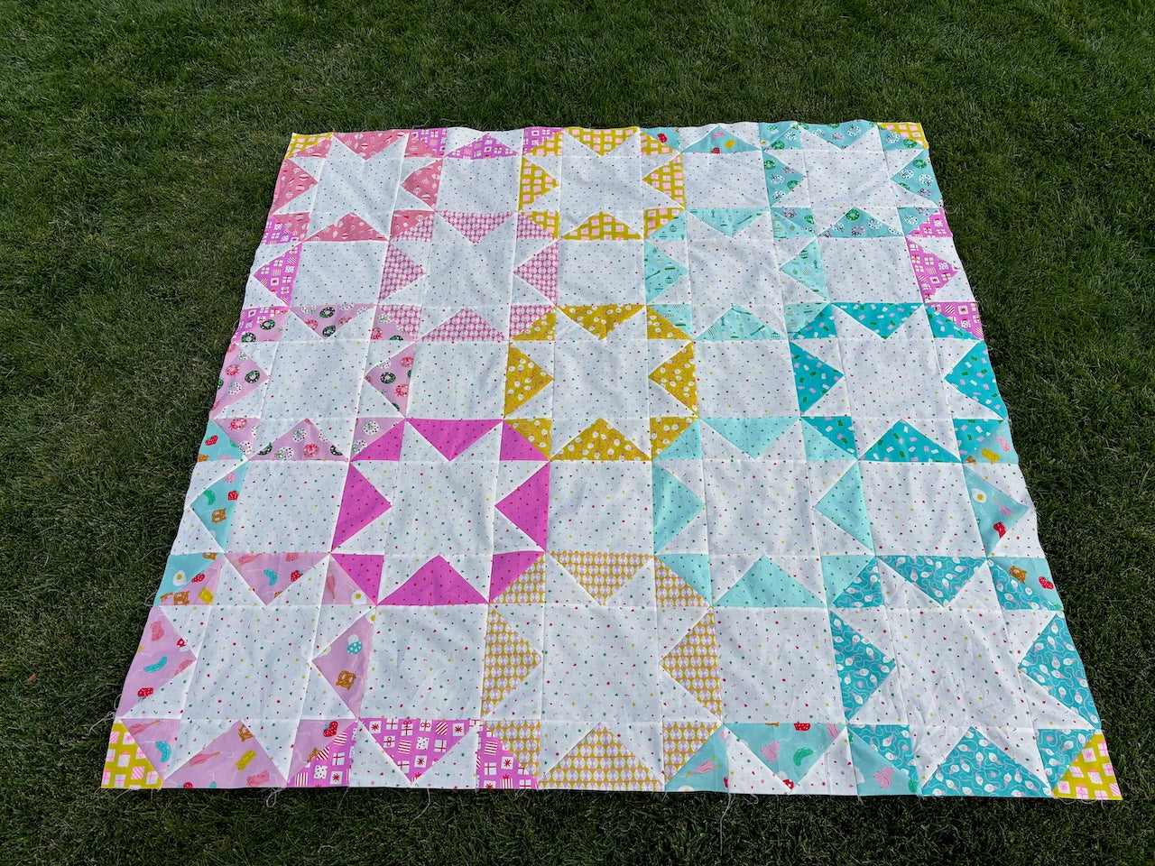 Colorful quilt with star patterns on a grassy background