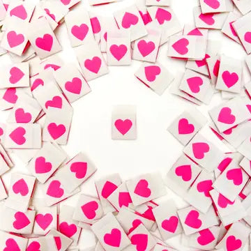 White tags with pink hearts scattered on a white background