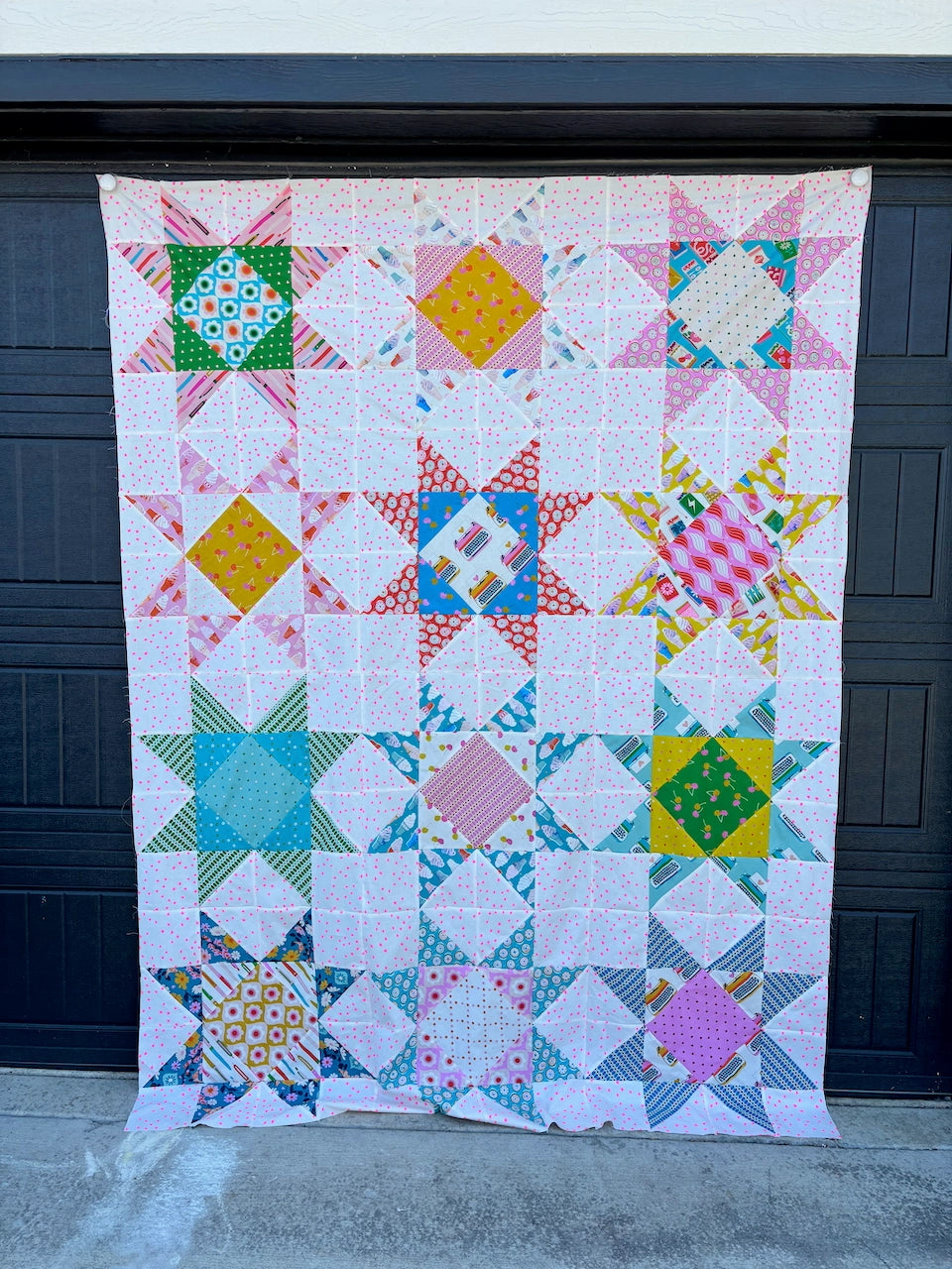Colorful quilt with geometric patterns hanging on a dark surface