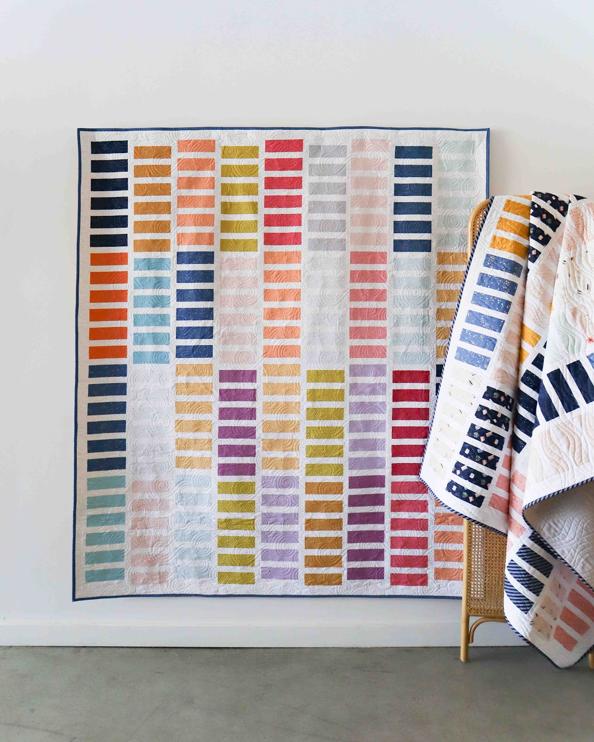 Colorful striped quilt on a wooden stand against a white wall